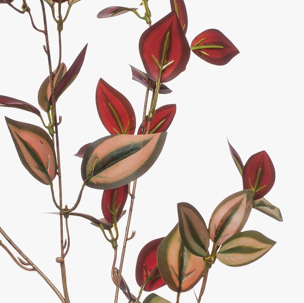 Künstlicher Zweig mit mehrfarbig gemusterten Blättern in Rot und Grün.