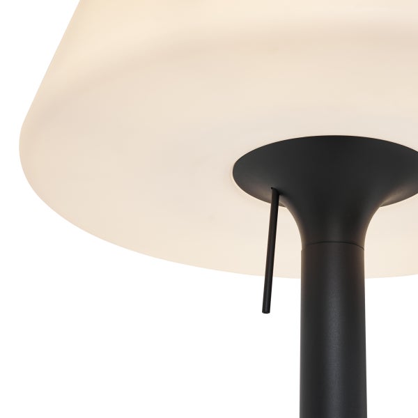 Nahaufnahme der Unterseite einer modernen Leuchte mit hellem Schirm, schwarzem Standrohr und integriertem Schalter.