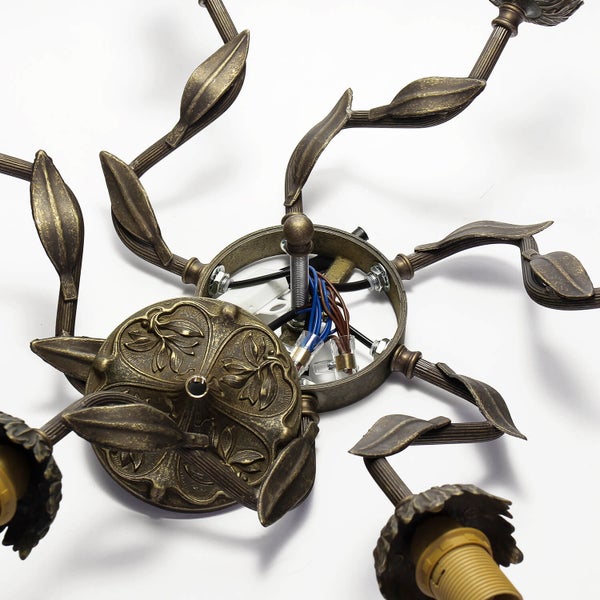 Detailansicht einer Deckenleuchte mit Blattornamenten und freiliegenden Anschlussklemmen.