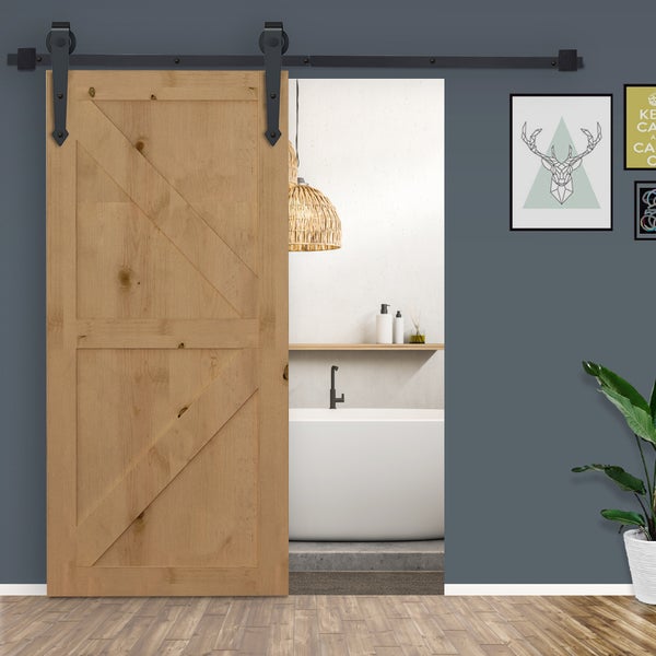 Schiebetür aus hellem Holz mit schwarzem Schiebetürsystem im rustikalen Design vor einem modernen Badezimmer mit Badewanne.