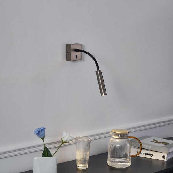 Wandleuchte mit flexiblem Arm montiert neben einem Nachttisch mit Dekoration