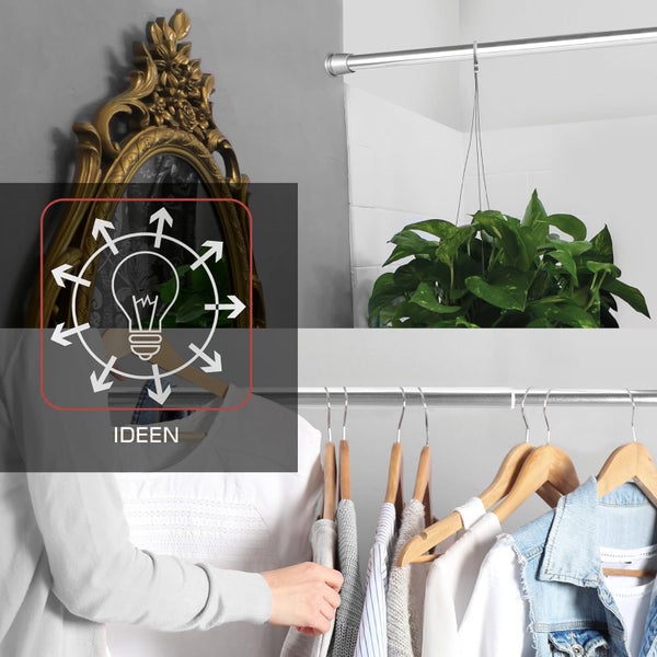 Kleiderschrank mit Kleidung an Holzbügeln, Spiegel, Topfpflanze und Ideen-Symbol