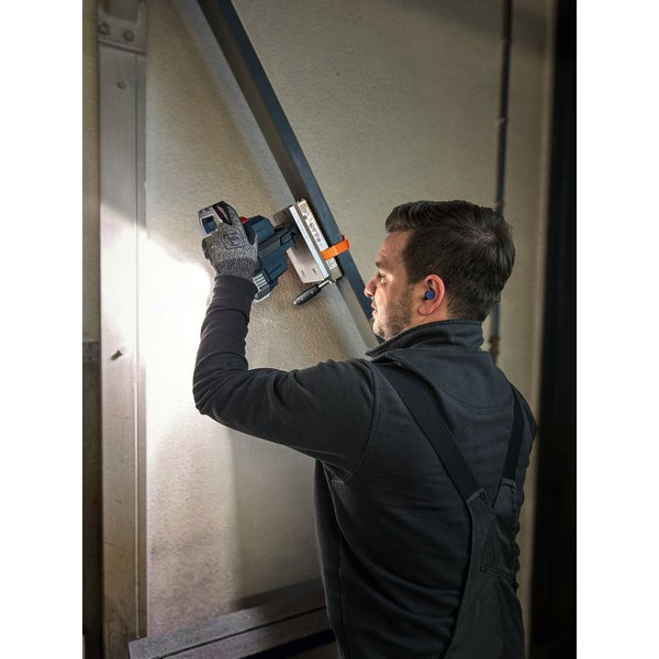 Handwerker bei der Arbeit mit einem Akkuhobel an einem Holzbalken in einer Werkstatt.