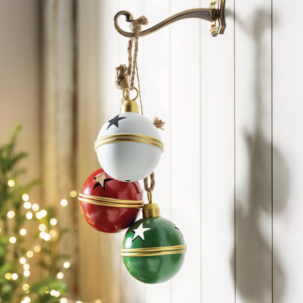 Drei hängende Weihnachtskugeln mit Sternmotiv als Weihnachtsdekoration an einem Wandhaken aus Metall.