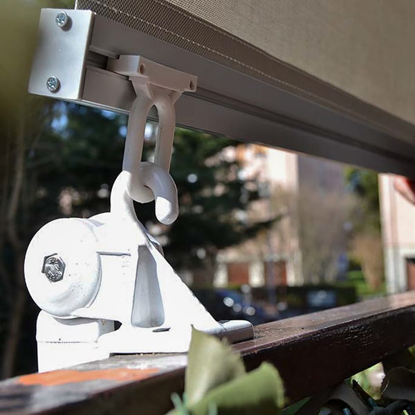 Nahaufnahme einer weißen Markisenbefestigung mit Haken und Öse aus Kunststoff und Metall an einer Schiene.