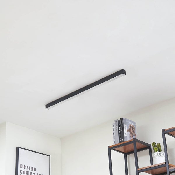 Lineare LED-Deckenleuchte in einem modernen, hellen Raum mit einem Holzregal und Wandbild.