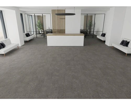 Großzügiger, moderner Empfangsbereich mit dunkelgrauen Bodenfliesen in Steinoptik, weißem Empfangstresen und Sitzbänken.
