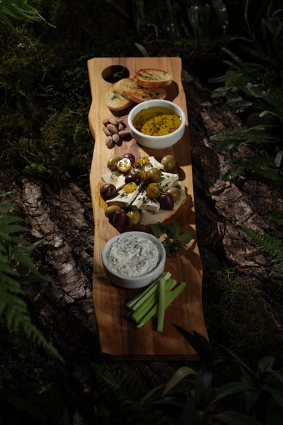 Holzbrett mit Antipasti, darunter Brot, Oliven, Käse und Dips