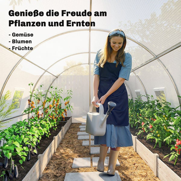 Eine Frau gießt Pflanzen in einem hellen, organisierten Folien-Gewächshaus mit Hochbeeten aus Holz und Gemüse wie Tomaten und Auberginen.