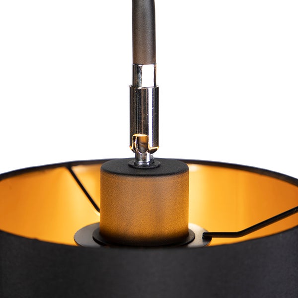 Detail einer Pendelleuchte mit schwarzem Textilschirm, goldfarbener Innenseite und verchromter Gelenkaufhängung.