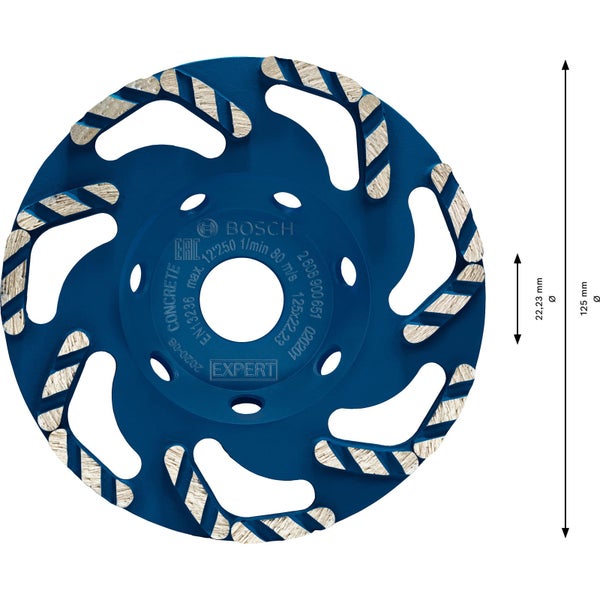 Ein Bauarbeiter verwendet eine Betonschleifmaschine an einer Wand. Er trägt Schutzkleidung und einen Helm.