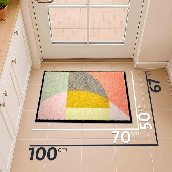 Fußmatte mit geometrischem Muster und den Maßen 100 x 67 cm vor einer Tür.
