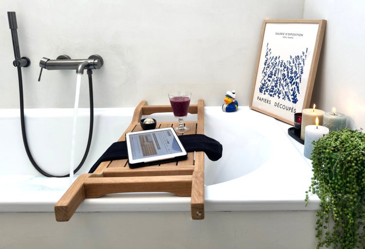 Badewanne mit Wasserhahn, Badewannenablage, Tablet, Getränk und Dekoration