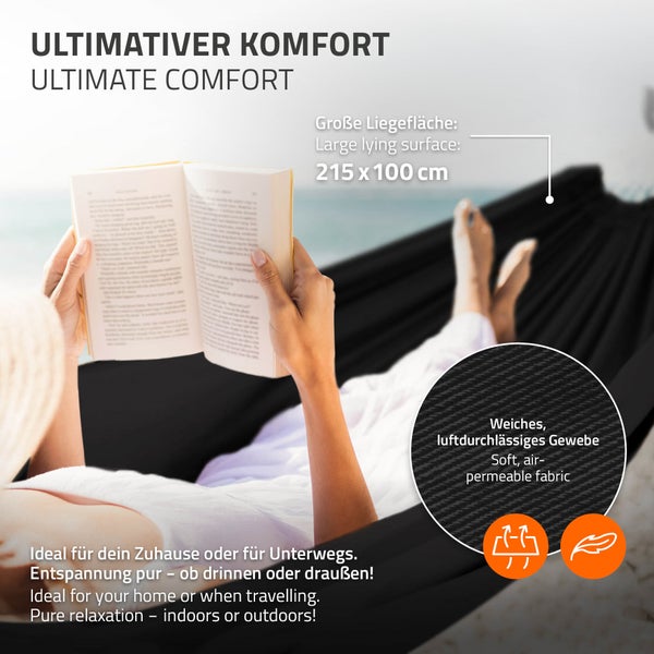 Person liegt entspannt in einer schwarzen Hängematte und liest ein Buch