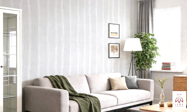 Modernes Wohnzimmer mit hell gestreifter Vliestapete, hellem Sofa mit grünem Überwurf und Stehlampe.