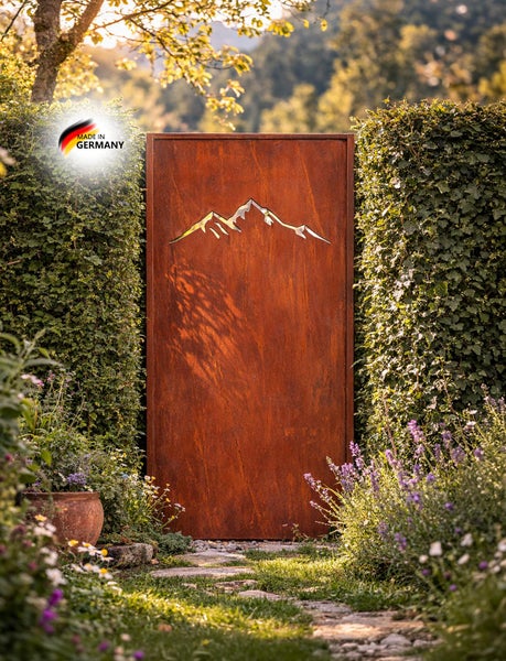 Sichtschutzelement aus Metall mit Edelrostoberfläche und Motiv Bergpanorama im Garten zwischen Hecken platziert mit Siegel Hergestellt in Deutschland