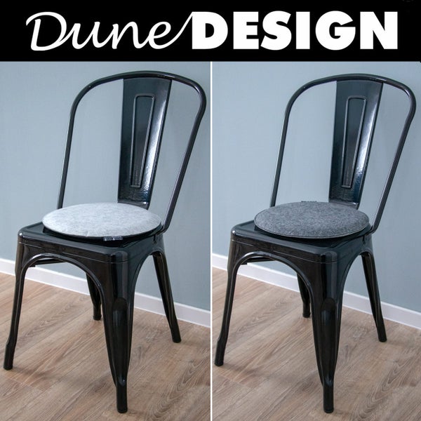 Dune Design Logo. Zwei schwarze Metallstühle mit runden Filzsitzkissen in einem hellen Raum mit Holzboden.