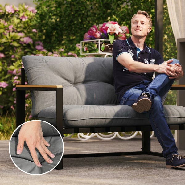 Modernes Gartensofa mit Metallgestell und grauen Polstern. Eine Person sitzt auf der Bank. Detailansicht zeigt Stoffstruktur und Polsterung.