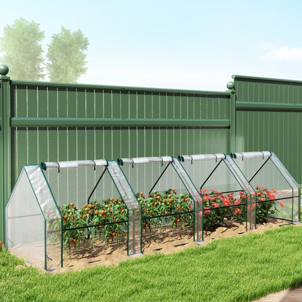 Folientunnel als Tomatenhaus mit Metallgestell im Garten vor einem Zaun stehend mit blühenden Pflanzen und Tomatensträuchern.