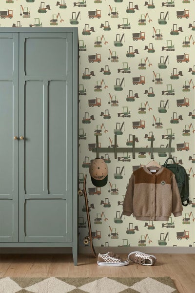 Tapete mit Baustellenfahrzeug-Muster in einem Kinderzimmer mit graugrünem Schrank und Garderobenleiste.
