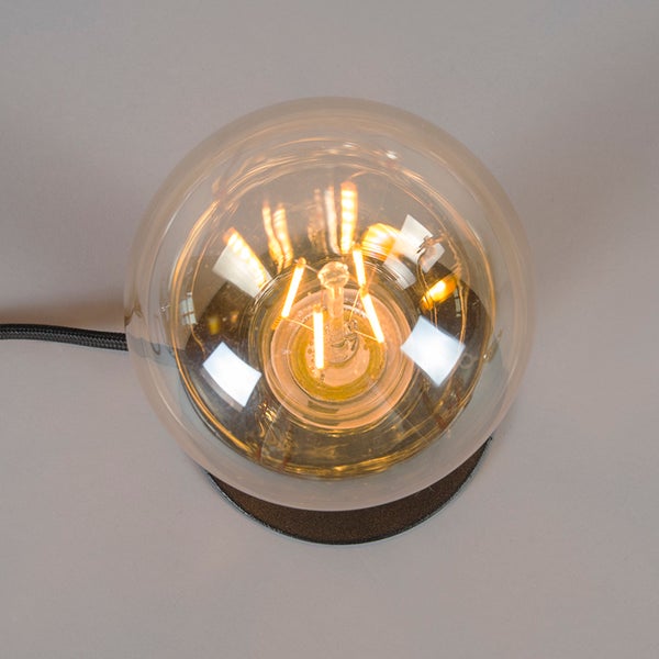 Draufsicht einer Tischleuchte mit runder Glaskugel und sichtbarem LED-Leuchtmittel im Filament-Design auf einem dunklen Sockel.