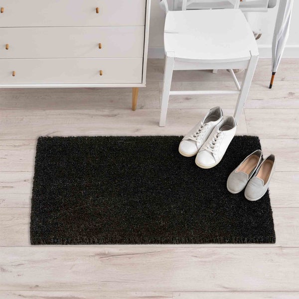 Schwarze Fußmatte im Eingangsbereich mit Kommode, Stuhl, Schuhen und Schirm