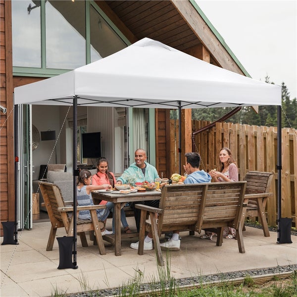 Eine Familie sitzt unter einem Pavillon im Garten und isst.