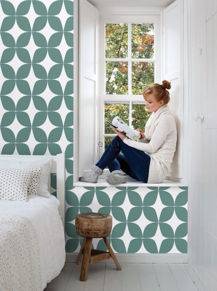 Helles Zimmer mit Bett, Fenster und Wand mit floralem Muster.