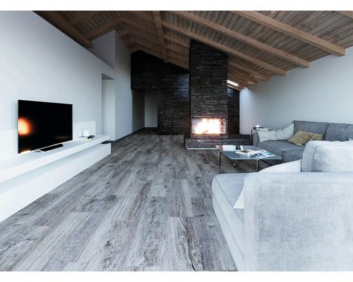 Modernes Wohnzimmer mit Bodenbelag in grauer Holzoptik, Dachschräge mit Holzbalken, Stein-Kamin und grauen Sofas.