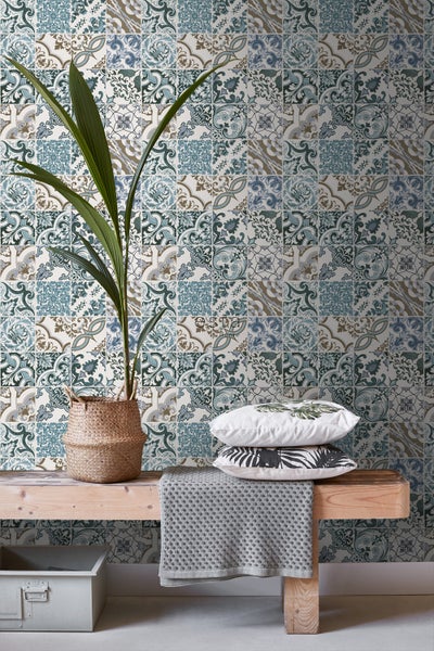 Dekorative Wandgestaltung mit Fliesenmuster, Pflanze im Korb und Kissen auf einer Holzbank