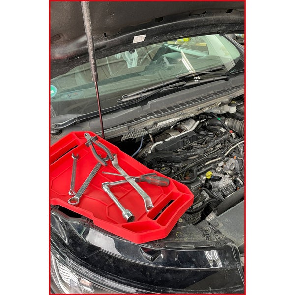 Rote Sandschaufel aus Kunststoff wird von zwei Händen gehalten