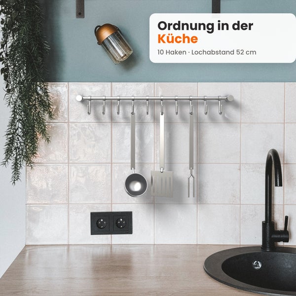 Küchenreling mit zehn Haken aus Metall, montiert an einer gefliesten Küchenrückwand über der Arbeitsplatte mit Spüle.