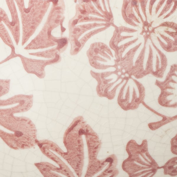 Nahaufnahme einer Keramikoberfläche mit Craquelé-Glasur und floralem Muster aus Blättern und Blüten.