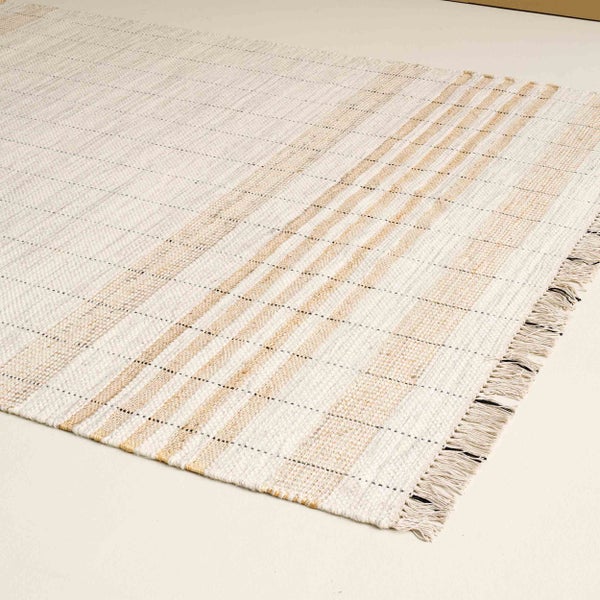 Gewebter Teppich in Creme und Beige mit Streifenmuster und Fransen.