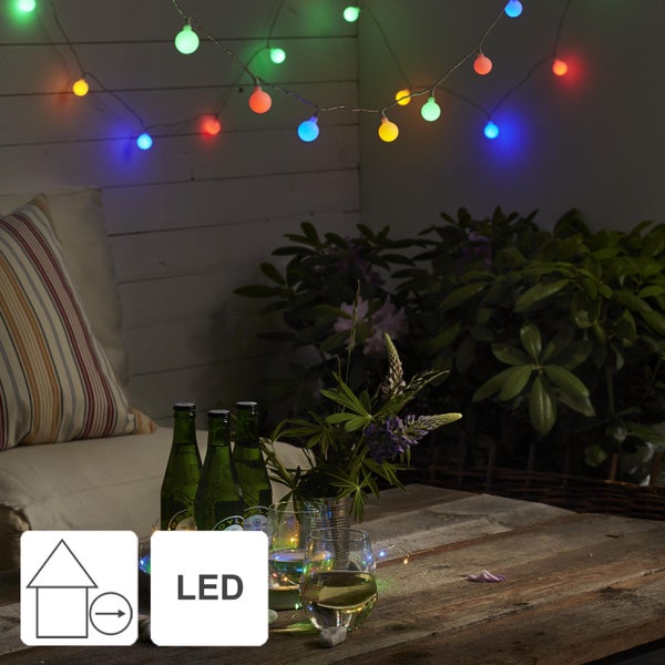 Dekorierte Terrasse mit Lichterkette, Getränken und Pflanzen für eine gemütliche Atmosphäre