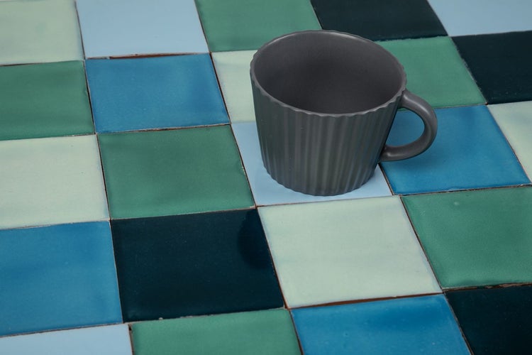 Fliesen in verschiedenen Blau- und Grüntönen mit einer grauen Tasse