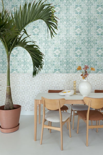 Helles Esszimmer mit Esstisch, Stühlen, Zimmerpflanze und gemusterter Tapete für ein gemütliches Ambiente.
