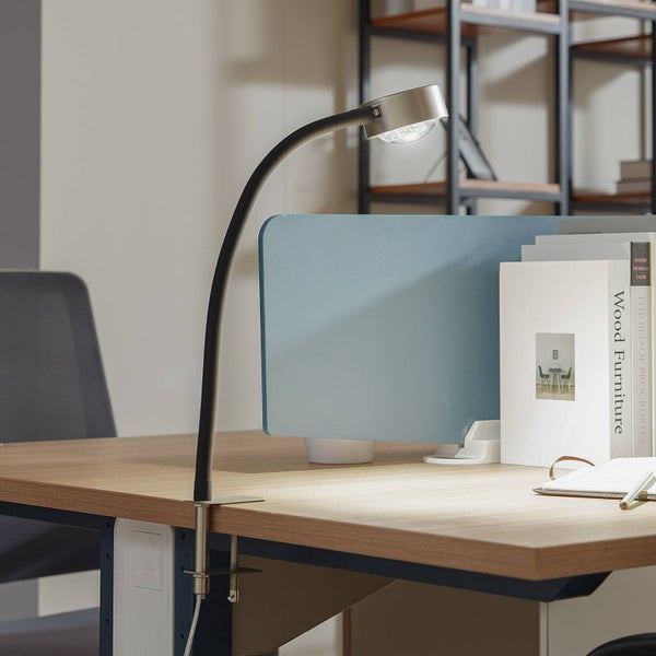 Klemmleuchte auf einem Schreibtisch mit Arbeitsplatzmaterialien