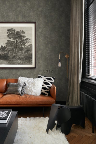 Wohnzimmer mit braunem Ledersofa, Zierkissen und einem schwarzen Elefanten-Hocker