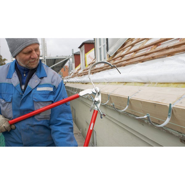 Ein Arbeiter verwendet eine Dachrinnenrichtzange zur Installation von Dachrinnenhaken am Dach eines Hauses.