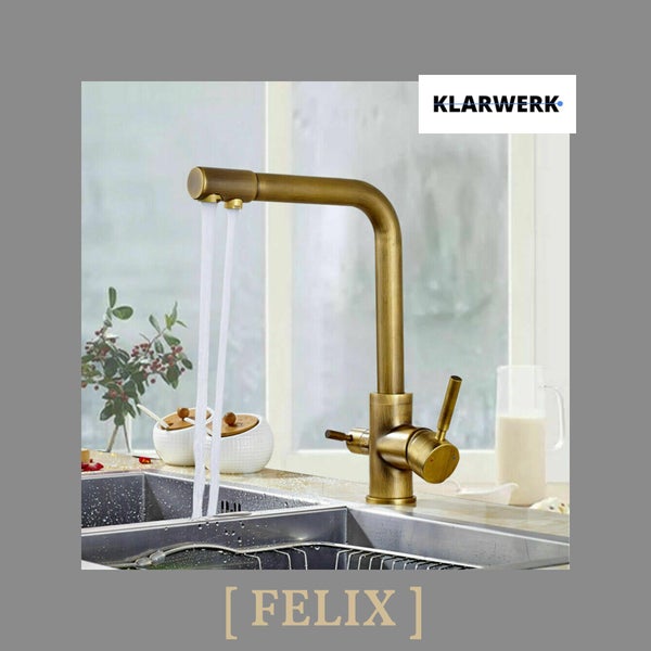 L-förmige Klarwerk Küchenarmatur Felix in Messing-Optik mit zwei Wasserläufen über einer Spüle in einer hellen Küche, Klarwerk Logo.