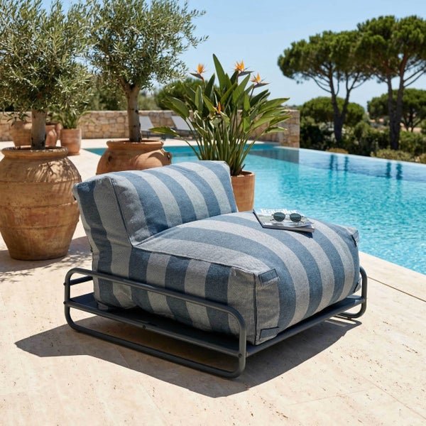 Moderner Outdoor-Loungesessel mit gestreiftem Kissen auf Metallgestell auf einer hellen Poolterrasse mit großen Terrakotta-Töpfen und Pflanzen.