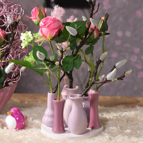 Dekorative Anordnung mit rosa Rosen, Weidenkätzchen und kleinen Vasen