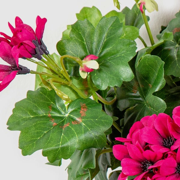 Künstliche Geranie mit pinken Blüten und grünen Blättern in der Detailansicht.