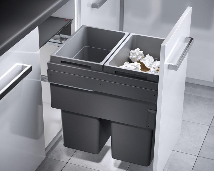 Ausziehbares Abfall-Trennsystem mit zwei grauen Kunststoffbehältern, eingebaut in eine weiße Küchenschublade.