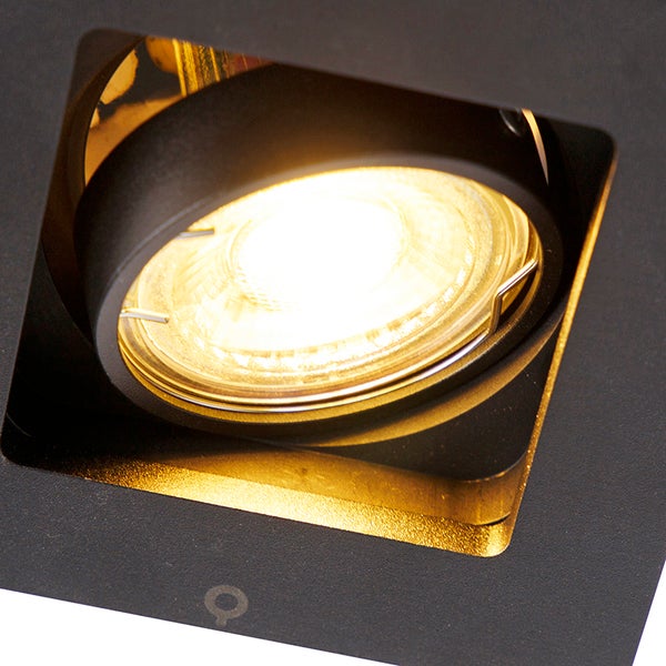 Nahaufnahme eines eingeschalteten, schwarzen, quadratischen Einbaustrahlers mit runder Lichtquelle.