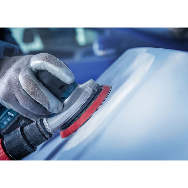 Ein Handwerker benutzt einen Exzenterschleifer auf einer Oberfläche.