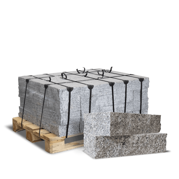 Granitsteine auf einer Holzpalette mit schwarzen Bändern gesichert und zwei Einzelsteinen im Vordergrund zur Ansicht der Steinstruktur.