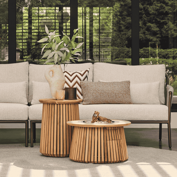 Moderne Terrasse mit hellem Lounge-Sofa, Kissen und zwei runden Beistelltischen aus Holzlamellen in hellem, organisiertem Ambiente.