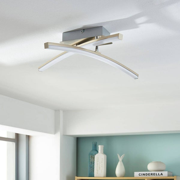 Moderne LED-Deckenleuchte mit zwei geschwungenen, überkreuzten Lichtbalken aus Metall und Kunststoff an einer weißen Decke.